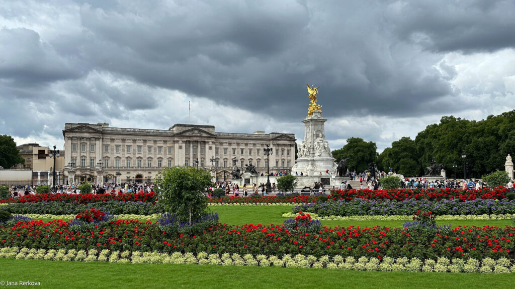 Exterior of Buckingham Palace with the Statue of Queen Victoria and blooming flowers in front