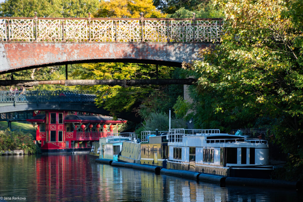 Regent's Canal with a barge in the front, and a  bridge and Chinese restaurant on a barge in the background