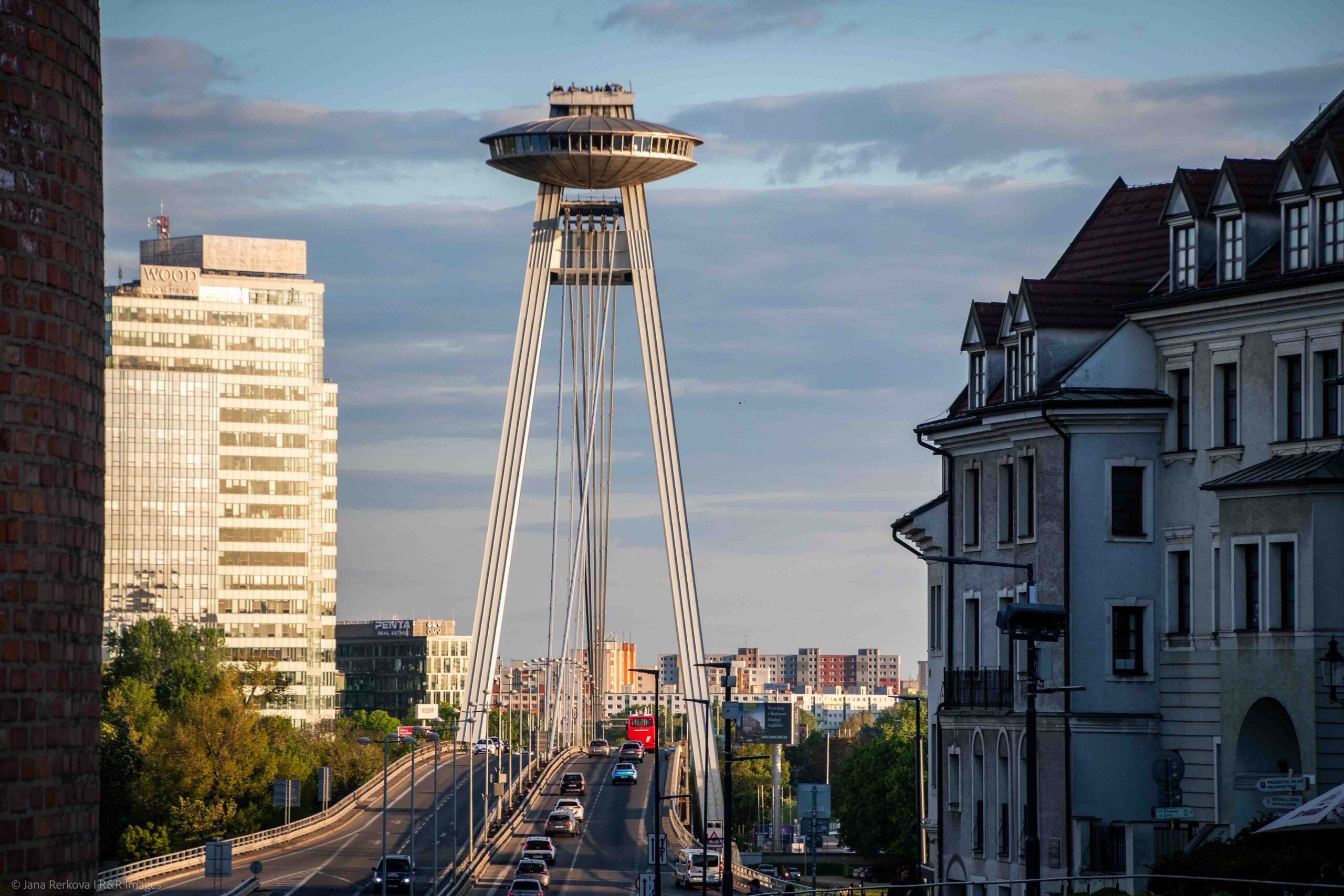 The modernist SNP Bridge stretching across the Danube River with the disc-shaped UFO tower rising above the structure